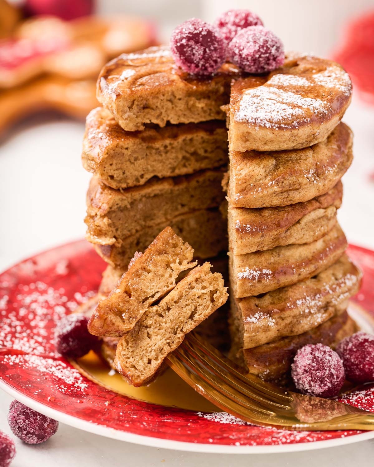 a bite of pancakes prepared on a fork resting on a plate of stacked gingerbread pancakes