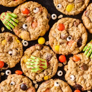 Overhead shot of monster cookies decorated with candy eyes and zombie hands on a dark background