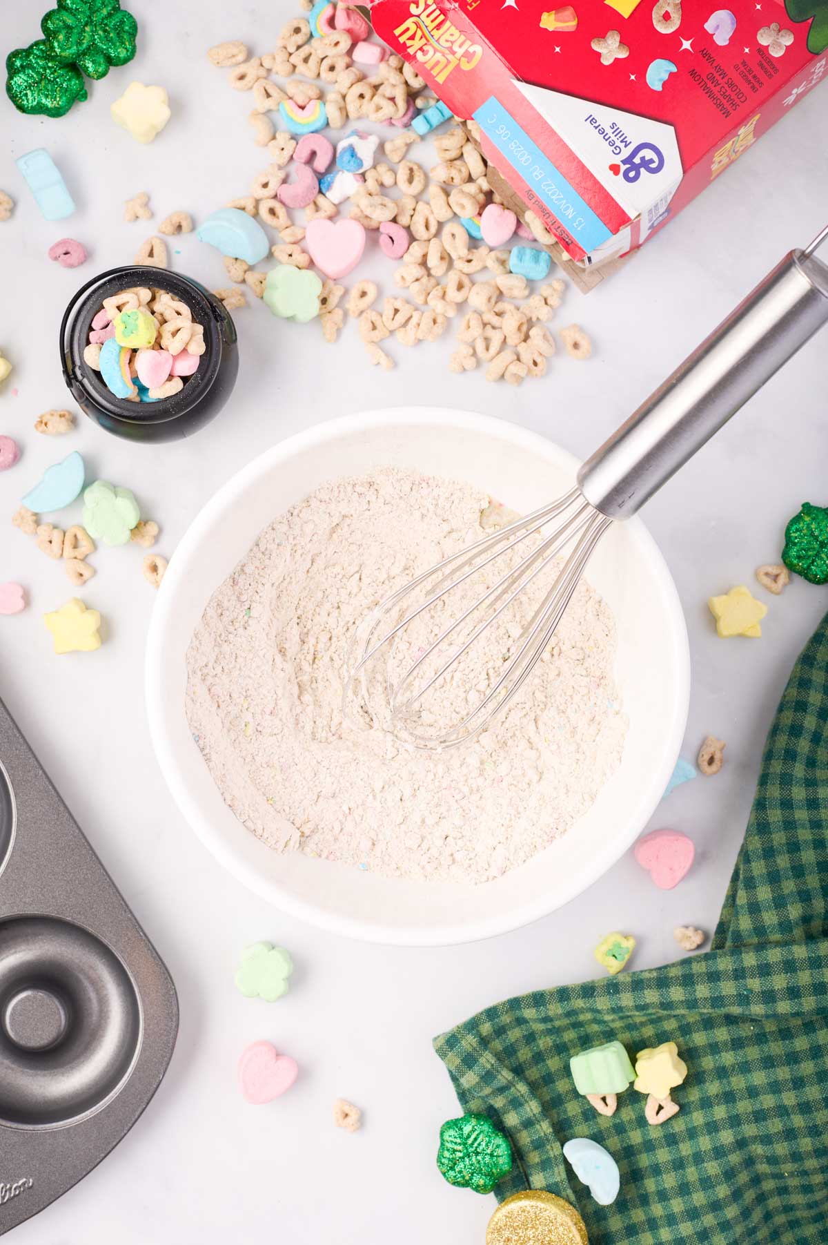 Dry ingredients for lucky charms donuts whisked in a small, white mixing bowl
