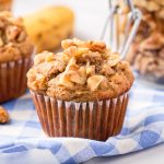 A Banana Walnut muffin sits on a checkered blue linen