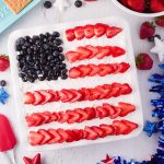 Stripes of strawberry slices and fresh blueberries create a flag design on top of a strawberry icebox cake