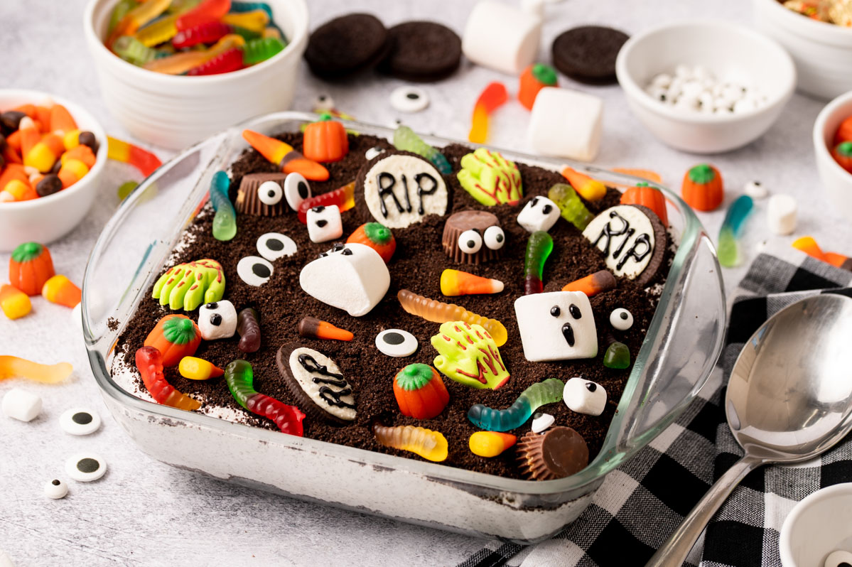 Halloween Candy dirt cake decorated with ghosts, gummy worms, oreos and pumpkins