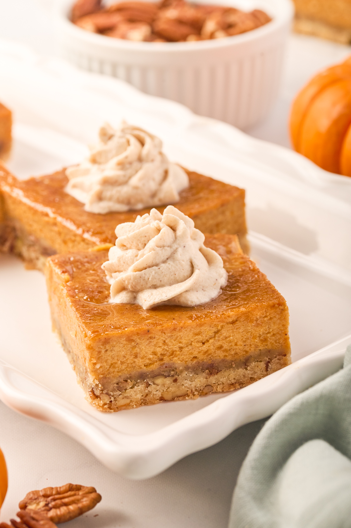 Two pieces of pumpkin pie bars on a scalloped white serving tray