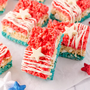 a stack of 4th of July rice krispie treats on a crinkled piece of wax paper surrounded by red, white and blue star decorations